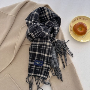 Detail of classic black and white plaid scarf with fringe and Elegant label on wool coat