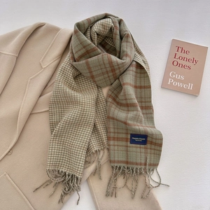 Close-up of a plaid tassel scarf with soft earthy tones and classic woven brand label
