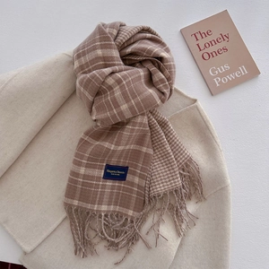 Detail of plaid scarf with tassels and elegant woven tag on a wool coat