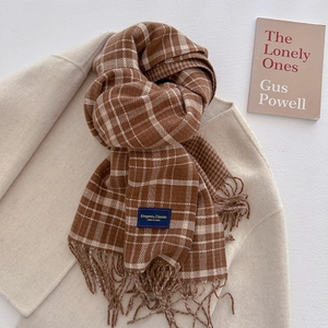 Close-up of caramel checkered scarf fabric texture with tassels on wool coat background