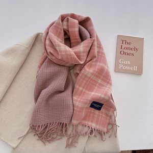 Pink and grey checkered tassel scarf elegantly layered over a warm beige wool coat