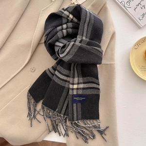 Close-up of black and white checkered scarf with fringe on a beige wool coat