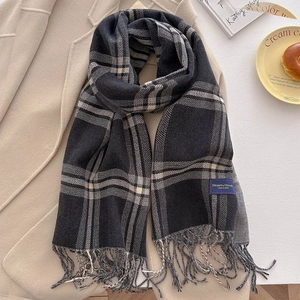Detail of soft cashmere-like plaid scarf with tassels and elegant woven label