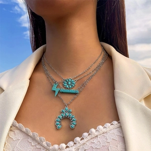 Detail einer mehrlagigen Boho-Silberkette mit Türkis-Anhängern an einem weiblichen Model