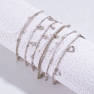 Minimalist silver heart and star beaded bracelet set on a white cylindrical display stand