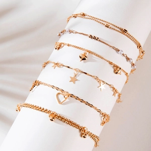 Detail of 6-piece gold bead bracelet set with heart, star charms and white pearls