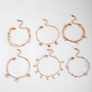 Detail of six-piece golden charm bracelet set with stars, hearts, and faux pearls