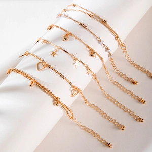 Detail of a 6-piece gold charm bracelet set with stars, hearts, and faux pearls