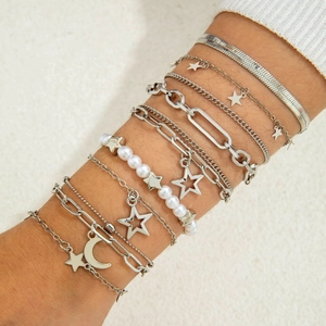 Detail of silver layered bracelet set with stars, moon charms, and pearls on wrist
