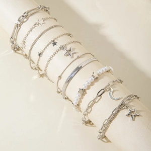 Detail of 9-piece silver bracelet set with star, moon and pearl charms on beige display