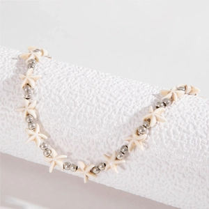 Close-up of white starfish beads and silver metal accents on a bohemian shell necklace