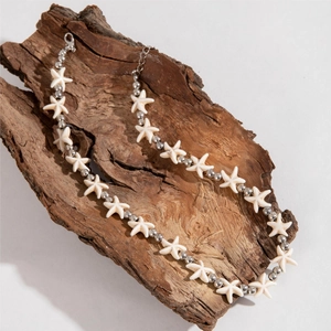 Detailed close-up of Bohemian starfish beaded necklace on rustic bark with metal clasp