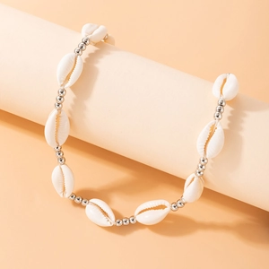 Close-up of white seashell and silver bead necklace on a beige display stand