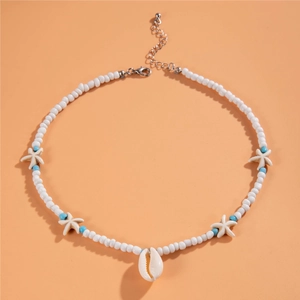 Detail of beach necklace with white starfish beads and shell pendant on orange backdrop
