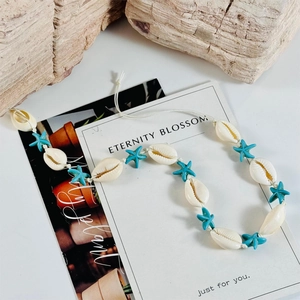 Detail view of handmade shell choker with starfish beads and white woven cord on stone