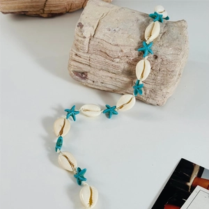 Detailed shot of bohemian sea shell and turquoise starfish beads on light rock background
