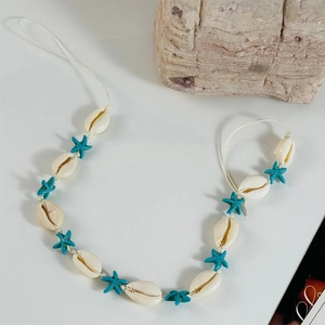 Close-up of white cowrie shells and blue starfish beads on a Bohemian beach necklace
