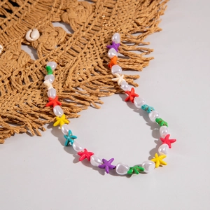 Detail of bohemian starfish necklace with colorful beads and white pearls on straw hat