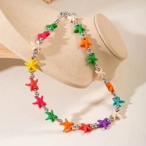 Macro detail of colorful starfish bead necklace with silver metal accents on a beige display