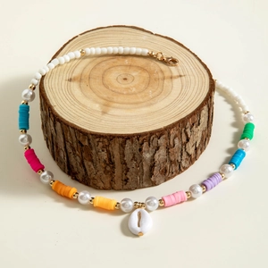 Detail of bohemian necklace with colorful clay beads, faux pearls and shell pendant
