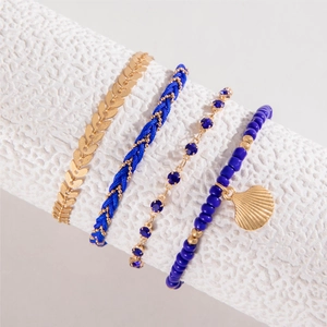 Detail of four-piece navy blue and gold bohemian bracelets with shell pendant and weave