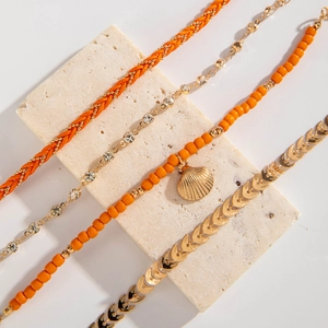 Detail of four-piece bohemian bracelet set with orange beads and gold shell pendant
