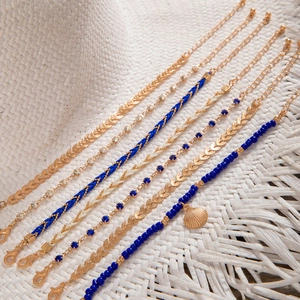 Detail of Bohemian multilayer bracelet set with blue beads and a gold shell pendant