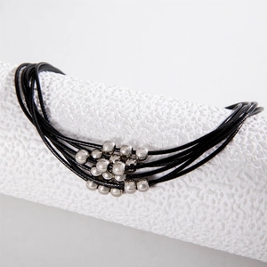 Macro detail of multi-layered black cord necklace with polished silver metal beads