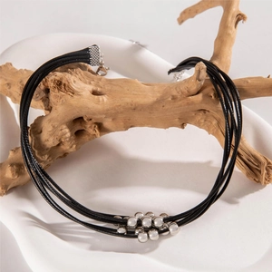 Multi-strand black cord necklace with silver metal beads displayed on a wooden prop