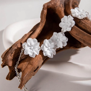 Collier élégant à pendentifs camélia blanc et chaîne argentée sur une branche naturelle