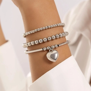 Detailed view of silver beaded chain bracelet set with a 3D heart pendant on a model