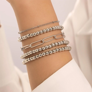 Close-up of stacked silver bead bracelets and paperclip chain on a model's wrist