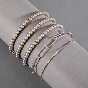 Detail of five-piece silver beaded chain bracelet set with heart pendant on grey display