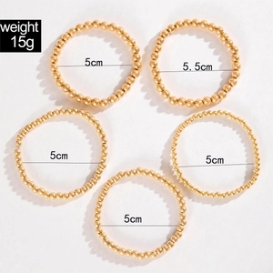 Set of five gold beaded stretch bracelets with metallic finish and heart pendant details