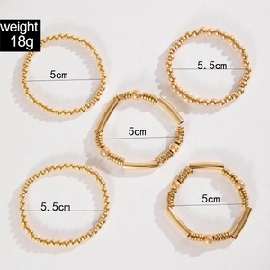 Five-piece set of gold beaded bracelets with textured metal rings and polished finish