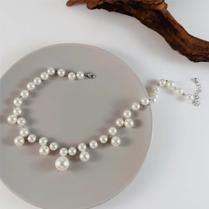Detail of irregular faux pearl necklace with silver lobster clasp on a grey display tray