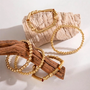 Stackable gold beaded bracelet set with circular link chains and polished metal finish
