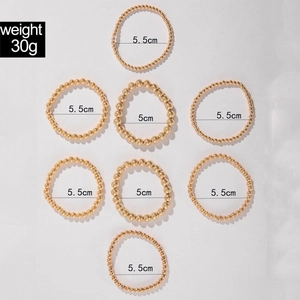 Detailed set of eight golden beaded elastic bracelets in various bead sizes and diameters