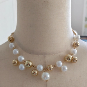 Detailed shot of irregular faux pearls and polished gold beads on a luxury necklace