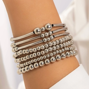 Detail of silver beaded bracelets and sleek metal bangles stacked on a wrist