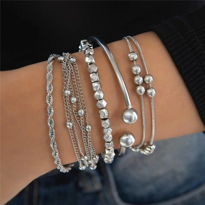 Detail of silver layered beaded bracelets with heart charms on model wrist