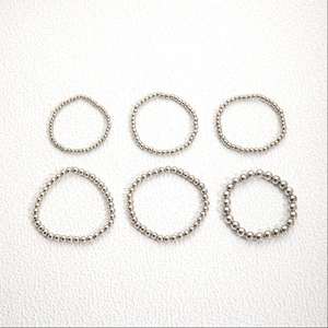 Minimalist six-piece silver beaded stretch ring set displayed on a white textured background