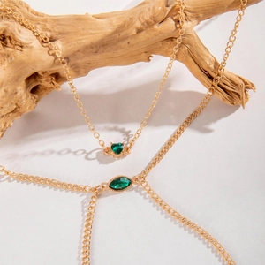 Detailed view of gold chain body jewelry with green heart and marquise cut emerald crystals