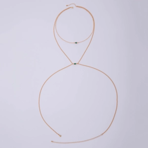 Detail of gold layered body chain featuring emerald green marquise cut crystal accents