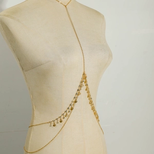 Detail of layered gold body chain with emerald-style rhinestones on a mannequin