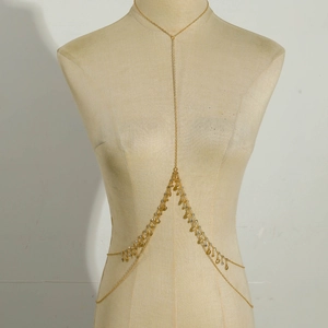 Detailed view of a golden body chain with teardrop sequins on a beige mannequin