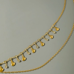 Golden double-layer body chain with shell pendants and crystal accents on grey background