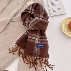 Detail of soft cashmere-feel striped scarf with tassel edges and blue woven label