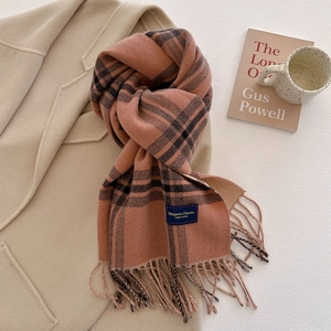Detailed macro view of an orange and black striped scarf with tassels and an elegant label