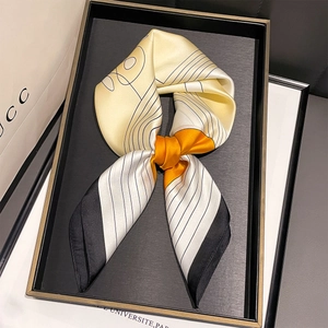 Dettaglio di un foulard di seta con motivi geometrici gialli e neri annodato a fiocco
